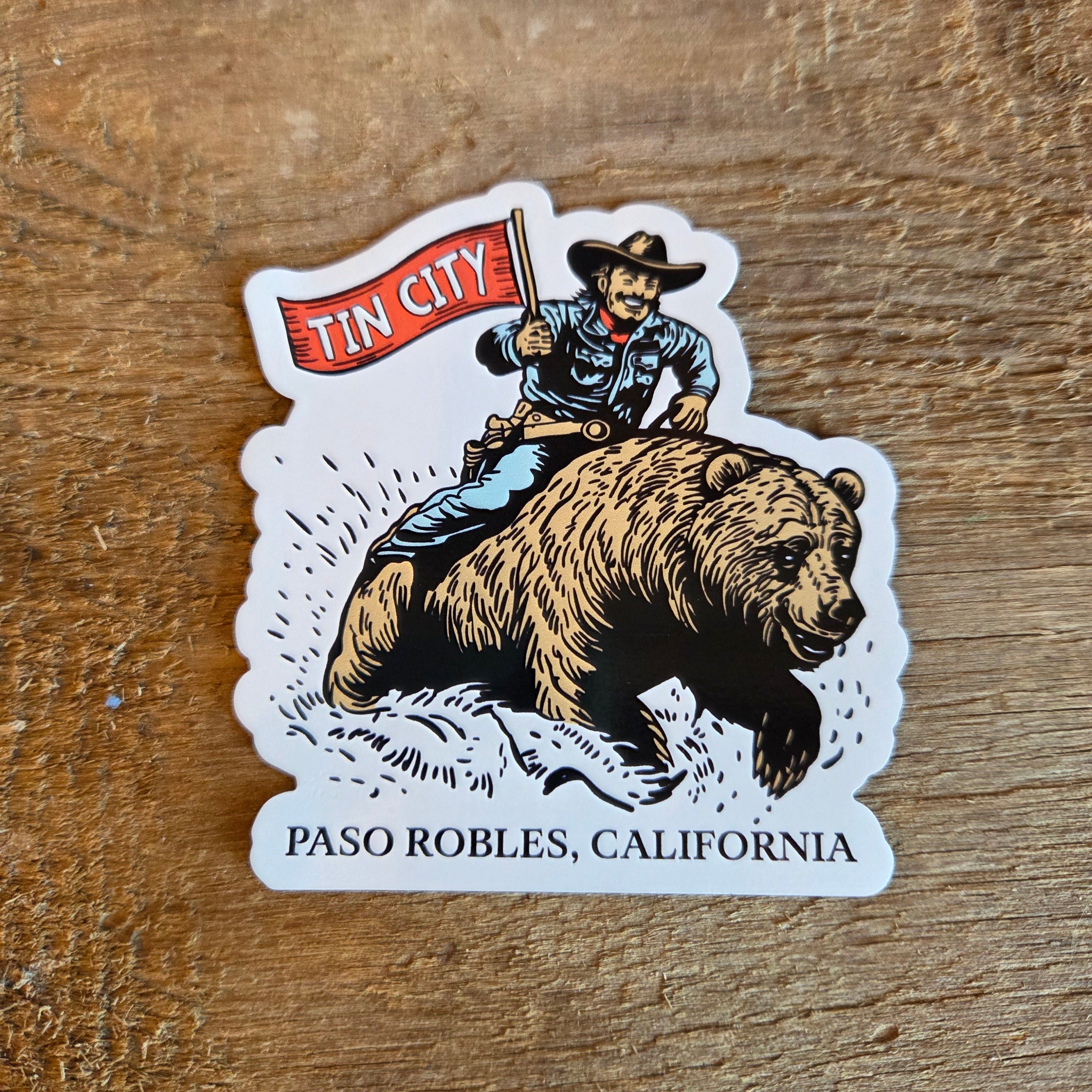 Magnet with bear and cowboy design on a wooden surface