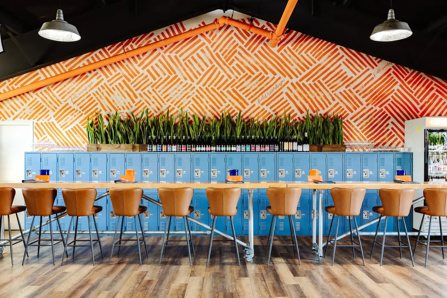Modern interior with blue lockers, orange geometric wall design, and wooden floor.